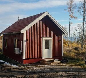 a small red building with a white door at Bokskogen stugby hus två in Jönköping