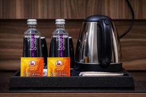 two bottles of soda and a tea kettle on a counter at منــازل الماسة للشقق المخدومة in Unayzah
