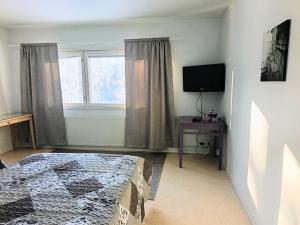 a bedroom with a bed and a tv and a window at Nivan Majoitus Nivan koulu in Joensuu