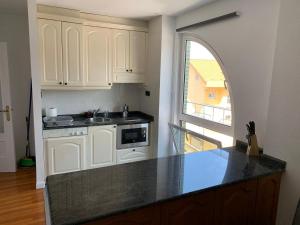 a kitchen with white cabinets and a black counter top at Apartamento somo SARR in Somo +6 photos