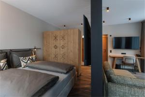 a bedroom with a bed and a couch and a table at Revier Boutique Hotel Kaprun in Kaprun