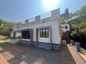 a white house with a balcony on top of it at Hillocks and The Spring in Sampaji