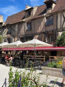 an old building with tables and chairs and umbrellas at Poitevins in Saint-Astier