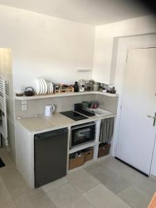 a small white kitchen with a stove top oven at Gipsy Chic Duplex on the beach in Carolles +8 photos