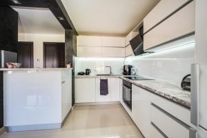a white kitchen with white cabinets and appliances at Villa Komitata-Pool and Jacuzzi in Balchik