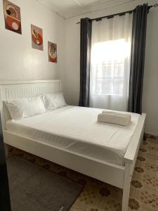 a white bed in a room with a window at Jenka homes in Kitui