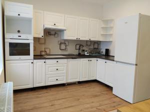a white kitchen with white appliances and wooden floors at Pod Dzikowcem in Boguszów-Gorce