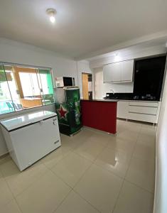 a kitchen with white appliances and a large screen tv at Casa de lazer 3Y in Maringá