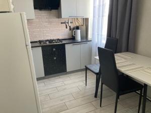 a kitchen with a table and two chairs and a kitchen with a stove at Apartment Artynova 29,світло завжди in Vinnytsya