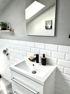 a white bathroom with a sink and a mirror at Urban Gold Apartment in Mostar