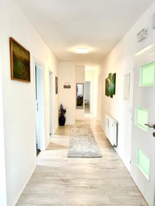 a hallway with white walls and a hardwood floor at Urban Gold Apartment in Mostar +4 photos