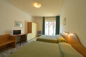a hotel room with two beds and a desk with a computer at Hotel La Balnearia in Alassio