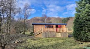 a wooden house with a deck in a field at Mòr Braw in Banavie