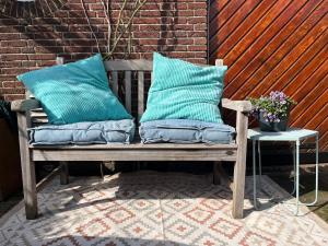 a wooden bench with two blue pillows on a patio at B&B De Holevoet in Scherpenzeel