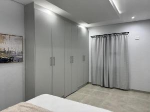 a bedroom with white cabinets and a bed in it at DECADE Self-catering in Swakopmund