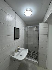 a white bathroom with a shower and a sink at DECADE Self-catering in Swakopmund