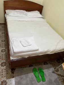 a bed with a pair of green shoes on the floor at Golf B&B in Nyahururu +1 photo