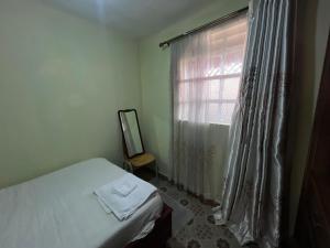 a bedroom with a bed and a window with a mirror at Golf B&B in Nyahururu