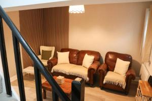 a living room with a leather couch and two chairs at Britannia Lodge in Howden