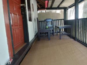 a porch with a bench and a red door at Cemara Paradise Homestay in Pulau Gilimelayu