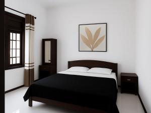 a bedroom with a black bed and white walls at Nimsara Homes in Veyangoda