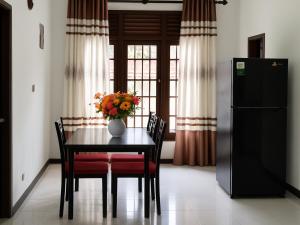 a dining room table with a vase of flowers on it at Nimsara Homes in Veyangoda +1 photo