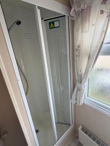 a shower in a bathroom next to a window at seton sands caravan in Port Seton