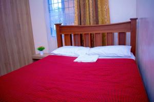 a bed with a red blanket and a towel on it at Eunia homes in Kibarani