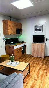 a living room with a table and a kitchen at Domek modułowyBursztynek in Rewa