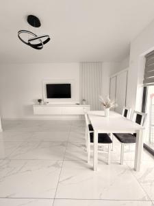 a white dining room with a white table and chairs at Apartamente & Studiouri Melia Eforie Nord in Eforie Nord