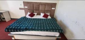a bed with a green blanket and red pillows at Lekhwar in Chamba
