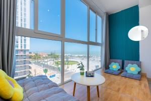 a living room with a couch and a table and large windows at Kozy Home Apartment in Vung Tau - Tam Thang Tower View & Back Beach step away in Vung Tau