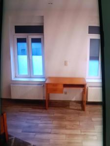 a wooden desk in a room with two windows at Nke Roméo in Liège