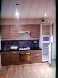 a kitchen with wooden cabinets and a white refrigerator at Nke Roméo in Liège