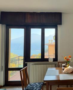 a dining room with a table and three windows at Casa Diana - Panoramablick auf den Gardasee in Pieve