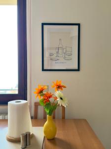 a yellow vase with orange and white flowers on a table at Casa Diana - Panoramablick auf den Gardasee in Pieve