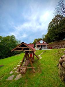 a picnic table in a field with a house in the background at JakLak in Izvoare