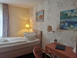 a hotel room with a bed and a desk with a laptop at Hotel am Wariner See in Warin