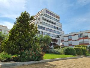 a tall white building with a tree in front of it at Écrin de Verdure - Design & Confort T2 38m2, WIFI, Piscine & Plage à 200m in La Grande Motte