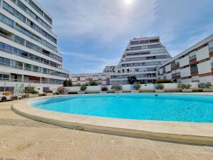 a swimming pool in front of two tall buildings at Écrin de Verdure - Design & Confort T2 38m2, WIFI, Piscine & Plage à 200m in La Grande Motte