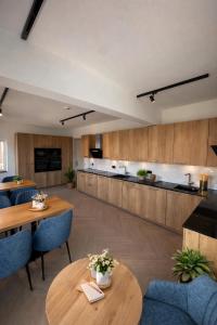 an open living room with tables and chairs and a kitchen at MSLiving Hotels in Hannover