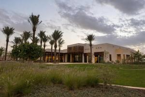 a building with palm trees in front of it at Daraah Resort - AMAALA in Ţaraf Shaqq al ‘Abd