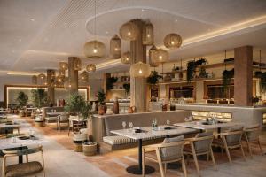 a restaurant with tables and chairs and chandeliers at Daraah Resort - AMAALA in Ţaraf Shaqq al ‘Abd