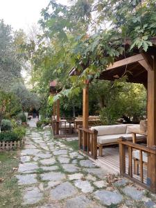a wooden pavilion with benches and tables in a garden at Pavelin yeri in Altınoluk