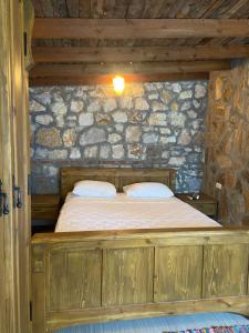 a bedroom with a wooden bed in a stone wall at Pavelin yeri in Altınoluk