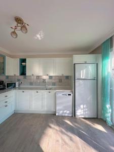 a kitchen with white cabinets and a refrigerator at Evalacati - Villa Harnup- Detached house with private pool and garden in Alaçatı