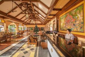 a woman standing at a counter in a restaurant with a large painting at Avalon Beach Resort Pattaya in Pattaya South