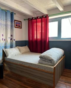 a bed in a room with a red curtain at Hotel Sakura in Jomsom