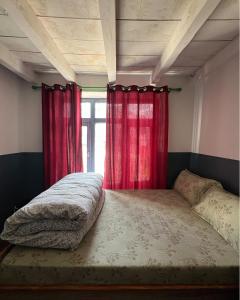 a bed in a room with red curtains at Hotel Sakura in Jomsom