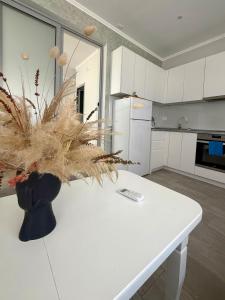 a white kitchen with a vase with a plant on a table at Dionis House in Shkodër